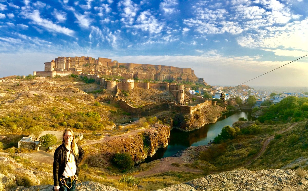 Laura ziplining in Jodpur's desert rock park with Mehrangarh Fort and the blue city of Jodhpur in the distance.